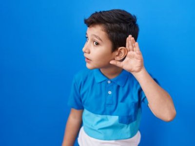 Young boy with his left hand cupped to his left ear.